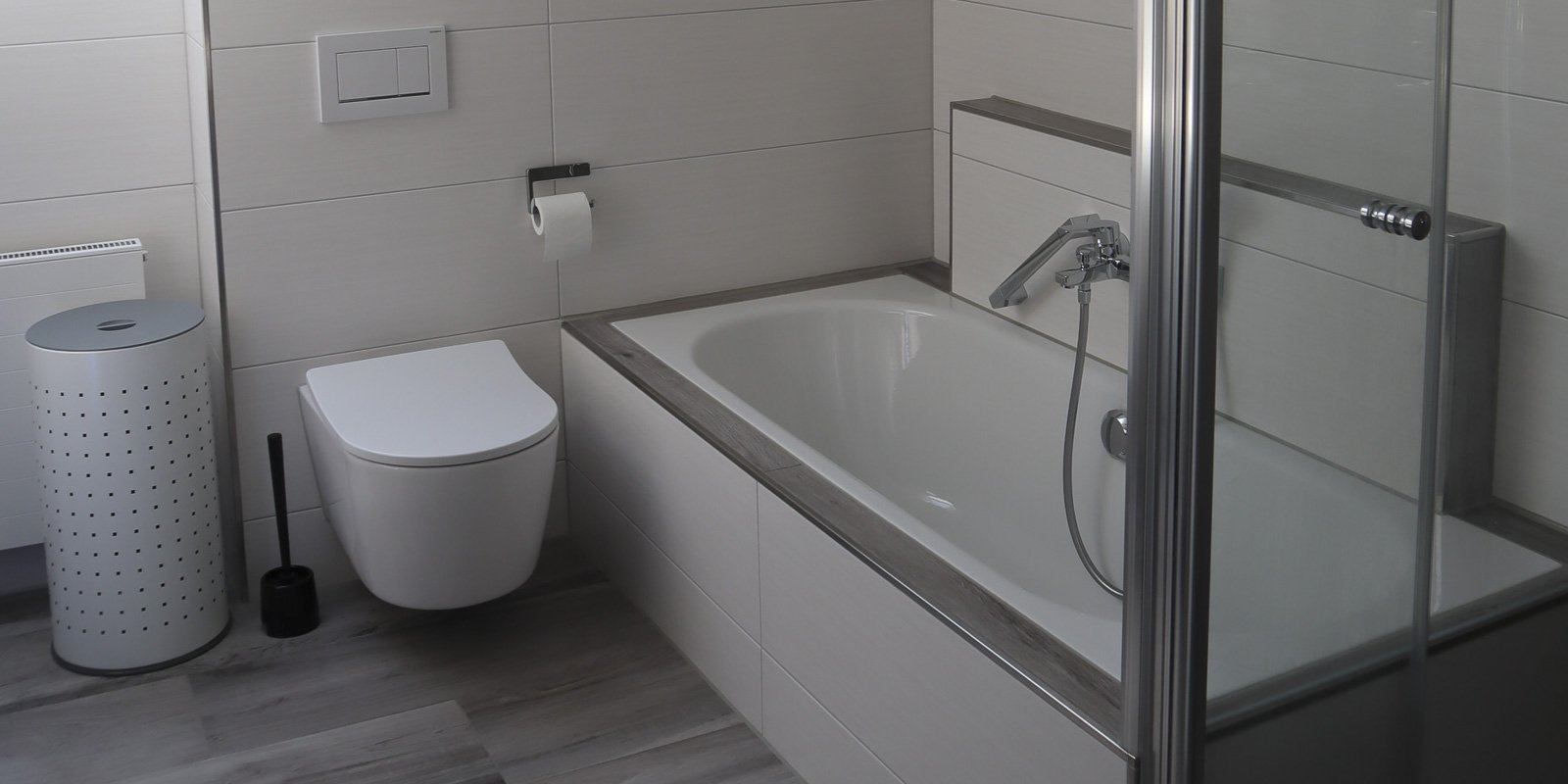 Ein modernes Badezimmer mit einer freistehenden Badewanne und einer eleganten Dusche aus Glas, die viel Licht reflektiert.