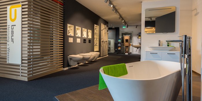 Ein modernes Badezimmer mit einer freistehenden Badewanne und einem grünen Handtuch, umgeben von stilvollen Sanitäranlagen.