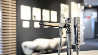 Ein glänzender Wasserhahn steht im Vordergrund, während der Hintergrund mit modernen Badezimmermöbeln und sanften Farben gestaltet ist.