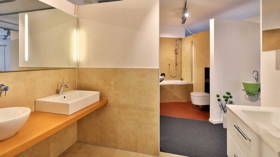 Ein modernes Badezimmer mit einer eleganten Holzablage, einem weißen Waschbecken und einem großen Spiegel, der das Licht reflektiert.