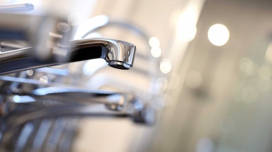 Nahaufnahme eines eleganten Wasserhahns, der mit seinem polierten Finish und den sanften Lichtreflexionen besticht.