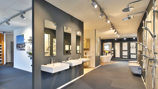 Ein modernes Badezimmer-Showroom mit eleganten Waschbecken und stilvollen Armaturen, die an einer dunklen Wand hängen.
