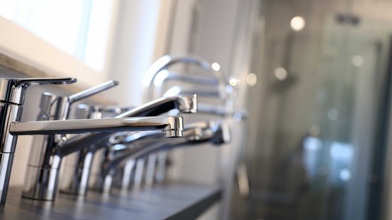 Die Nahaufnahme von eleganten, polierten Wasserhähnen zeigt deren modernes Design und die reflektierenden Oberflächen.