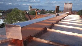 Ein Kupferdach mit schimmernden Platten bietet einen Blick auf die Stadt, während Wolken am Himmel vorbeiziehen.