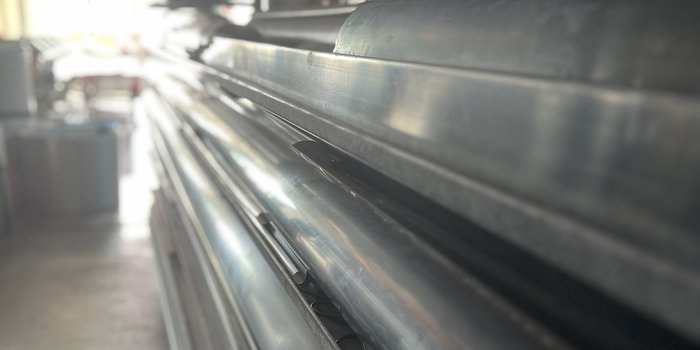 Eine Reihe von glänzenden Metallrohren, die ordentlich gestapelt sind, reflektiert das Licht in einem industriellen Umfeld.
