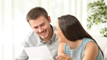 Ein Mann und eine Frau lachen sich an und halten ein Blatt in der Hand